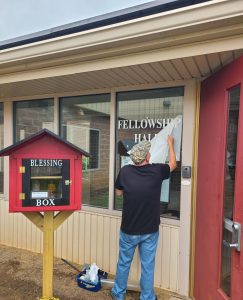 Adams Signs installing a temporary vinyl sign for Newcomerstown Christ Methodist Church