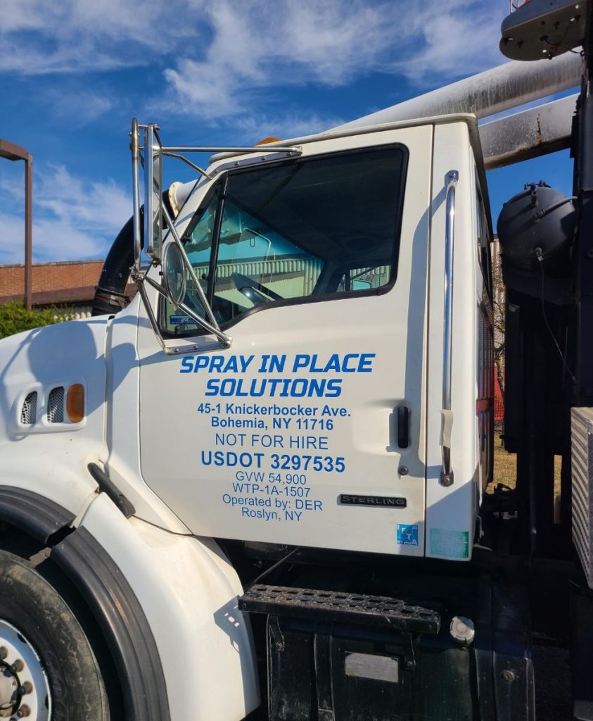 A white work truck with blue applied vinyl lettering of the company's name on the drivers door