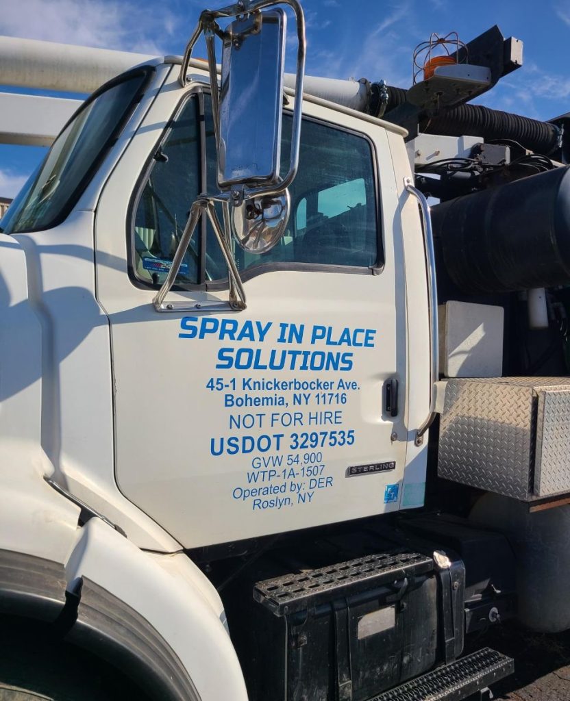 A white work truck with blue applied vinyl lettering of the company's name