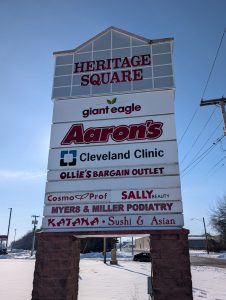 Heritage Square plaza monument sign displaying multiple tenant panels including Cleveland Clinic Union Hospital, mounted on brick columns in Dover, Ohio