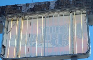 Interior of an open cabinet sign cabinet showing fluorescent light tubes and the reversed Molly Brown's Cafe graphic on the new sign face, viewed from the back during installation in Massillon, Ohio