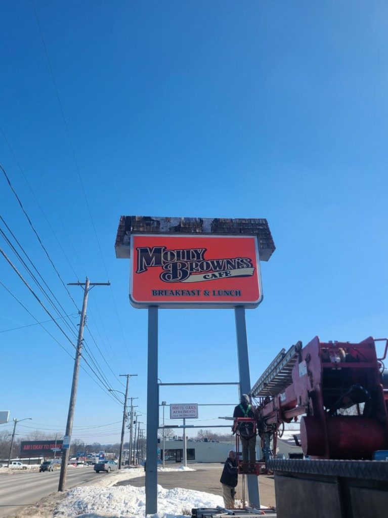 Completed Molly Brown's Cafe cabinet sign face on a dual-post pylon structure displaying the red and navy Breakfast and Lunch branding along a roadside in Massillon, Ohio
