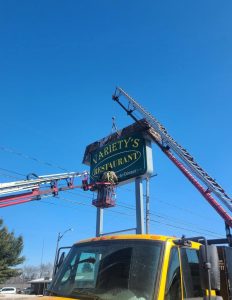 Adams Signs technician in aerial lift removes the Variety's Restaurant cabinet sign face from a pole-mounted structure during a sign face replacement in Massillon, Ohio