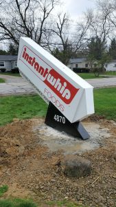 Side view of the newly installed Instant Whip Foods angled specialty sign showing the white wedge cabinet with red brand logo, FOODS lettering, and black base displaying address number 4870 in Akron, Ohio | Adams Signs & Graphics