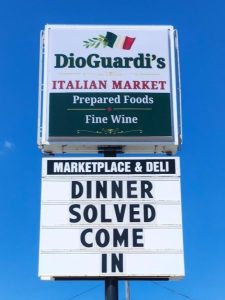 Illuminated pylon sign for DioGuardi's Italian Market with changeable reader board standing roadside near passing traffic in Canton, Ohio | Adams Signs & Graphics