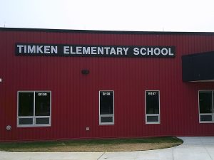 Dimensional letter wall sign reading Timken Elementary School mounted above classroom windows on the red metal building facade | Adams Signs & Graphics