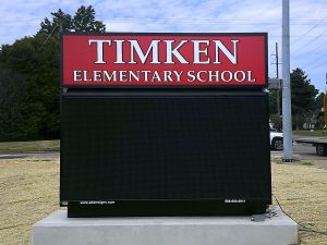Illuminated Timken Elementary School header sign mounted atop a blank LED message center on a concrete base | Adams Signs & Graphics