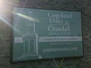 A close up view of an illuminated stone mounted sign for Copeland Oaks and Crandall Medical Center displaying the website address | Adams Signs & Graphics