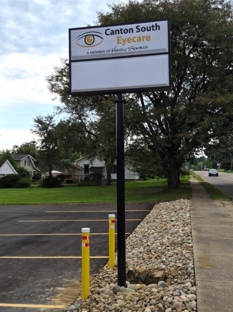 Front view of the Canton South Eyecare pole sign above a freshly landscaped stone bed with protective yellow bollards | Adams Signs & Graphics