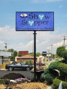 Illuminated pole sign for Show Stopper Garden Center and Fruit Market with a jewel logo above a roadside garden display | Adams Signs & Graphics